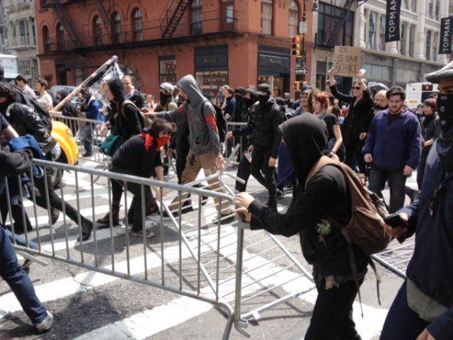 Black bloc using police barricades to wall off cops